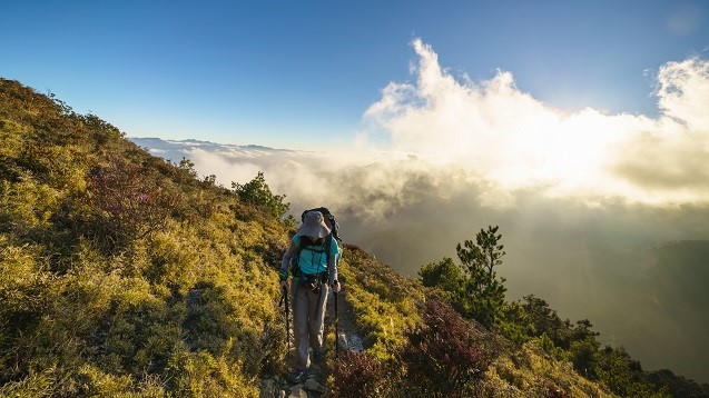 傍晚時分，溫暖的斜射光線打亮雲朵、山谷與我們步行的身影