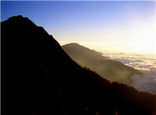 夕陽餘暉下的雲海，恰巧落於高大山峰的下切支脈 									壯麗的山壁，在逆光的效果之下更具震撼力